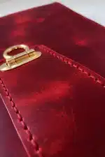 Kırmızı hakiki deri organizer detay çekim, el dikişi kenar ve metal toka mekanizması